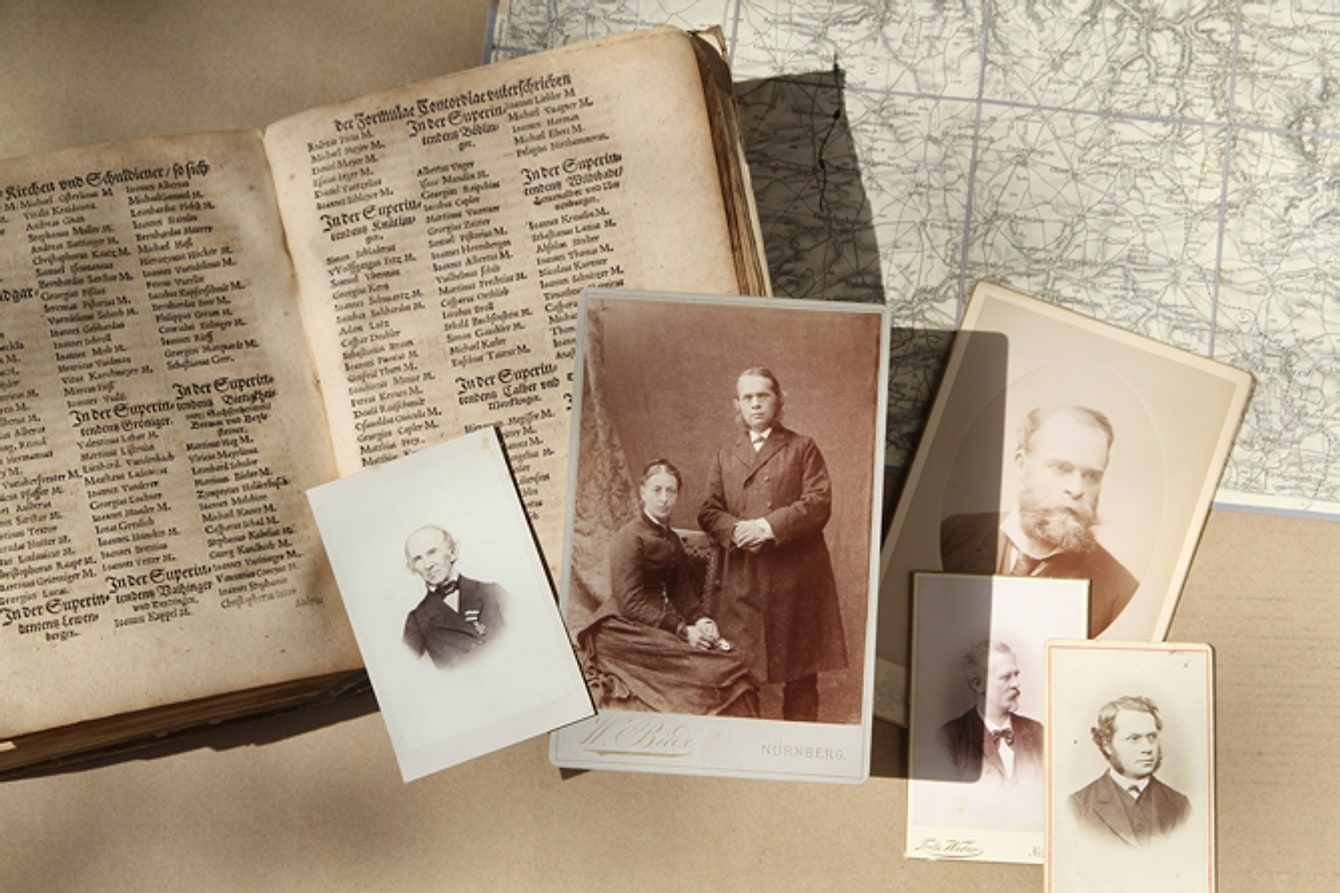Altes Kirchenbuch, historische Landkarte und Porträtfotografien aus dem 19. Jahrhundert auf einem Tisch